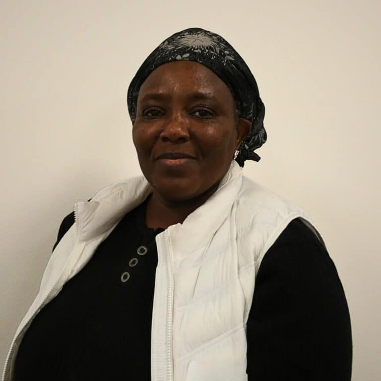 May contain a person wearing a black headscarf and white vest over black top.